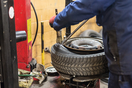 汽车维修车间摄影照片_专业汽车修理工在汽车维修服务中更换车轮上的轮胎。
