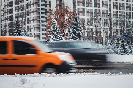 一辆行驶中的汽车在雪中的冬季道路上沿着一座高楼行驶