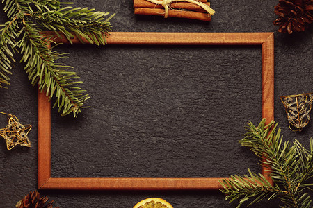 圣诞树枝摄影照片_圣诞作文、贺卡或其他设计的空白 — 带木框的圣诞树枝和深色背景上的装饰、平躺、顶视图、复制空间、文本位置