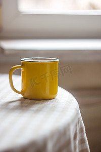 阳光明媚的桌子上放着一杯黄色的咖啡茶