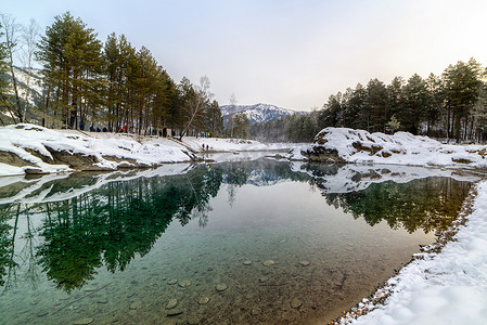 冰池塘摄影照片_冬天在群山和树木之间的高山湖泊