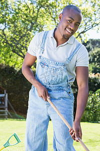 穿着工装裤的年轻人在花园里扫地