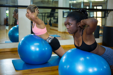 普拉提课程摄影照片_两名健康的女性在健身球上表演普拉提
