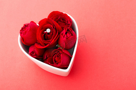 红色玫瑰和钻石戒指在红色 b 上的心形碗内