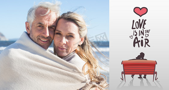 海滩上裹着毯子的微笑情侣的合成图像