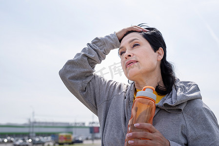 在公园户外艰苦锻炼后擦汗的老年妇女