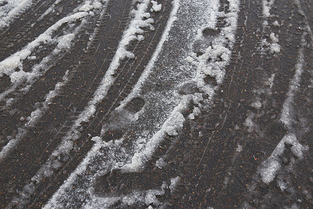 雪街道摄影照片_柏油路上融化的雪中的轮胎痕迹