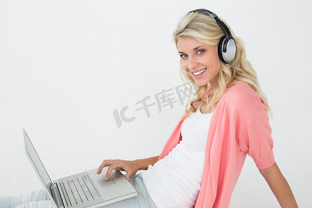 美丽的女人一边听音乐一边使用笔记本电脑