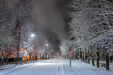 在多雪的树中的冬天路在晚上。