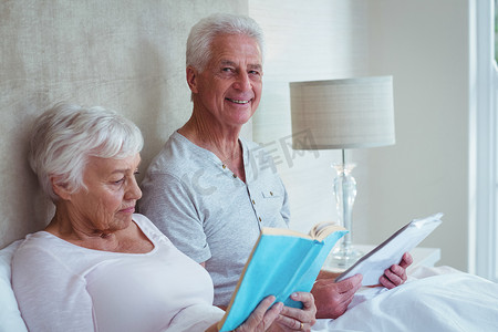 快乐的老人和妻子在卧室看书