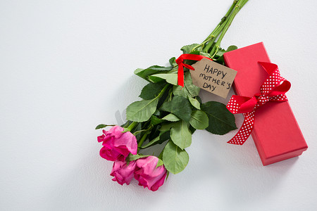 粉色玫瑰摄影照片_礼盒和一束粉色玫瑰，上面写着母亲节快乐的标签