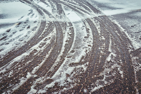 柏油路上融化的雪中的轮胎痕迹