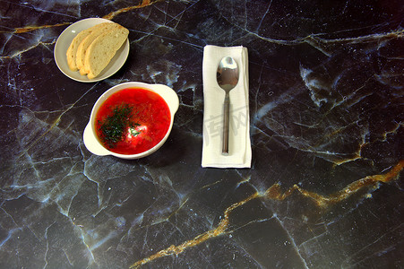 传统的俄罗斯汤罗宋汤、白面包和一把勺子放在餐巾纸上。