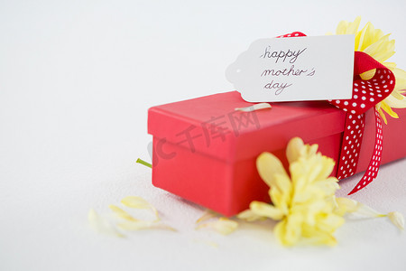 花标记摄影照片_有愉快的母亲节标记和黄色花的礼物盒