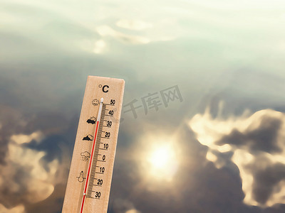 30天摄影照片_显示 30 度热量的温度计以湖水为背景，有云和太阳的反射