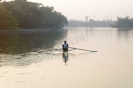 个人运动速度划船者在单人双桨船员划艇滑动赛艇外壳在湖水桨上运动坐在滑动索具座椅上做运动，在日落时进行健身锻炼。