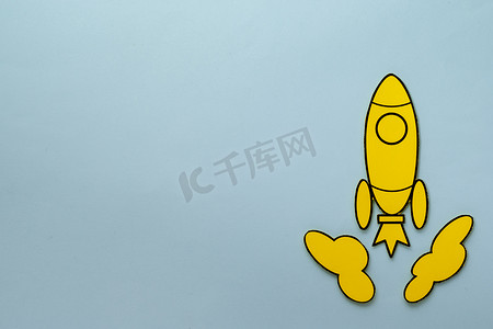 升空卡通摄影照片_黄色卡通火箭在蓝色背景中飞速飞行
