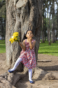 穿着裙子的小女孩手里拿着一束花在公园里庆祝