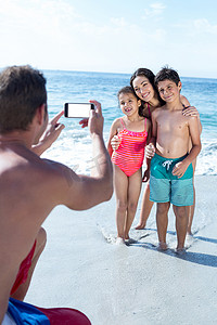 父亲在海边给孩子和妻子拍照