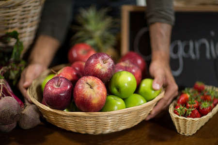 小贩在杂货店拿着一篮子苹果