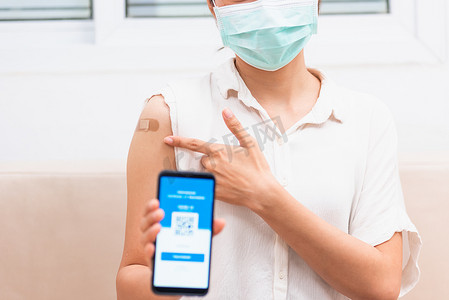 预防三高摄影照片_女人指着手臂上的胶布，她接种了疫苗，并展示了应用程序智能手机移动数字屏幕接种疫苗