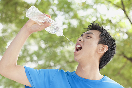 年轻人在公园里喝瓶装水