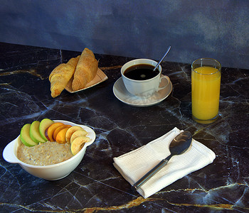 一杯橙汁摄影照片_传统的健康早餐、水果燕麦片、一杯黑咖啡、两个羊角面包和一杯橙汁。
