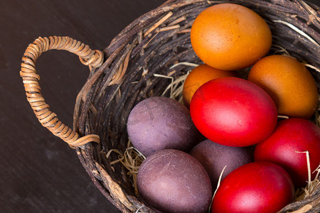 柳条篮子，木制的桌子上放着五颜六色的复活节彩蛋。