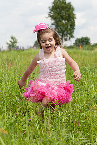 一件桃红色礼服的小女孩跑在草