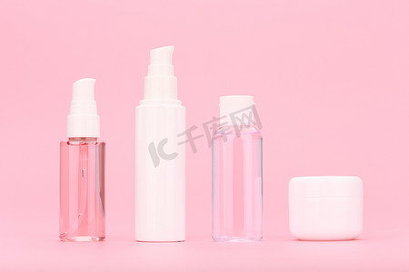 粉红色背景下的一组无品牌化妆品瓶，配有清洁凝胶、面霜、乳液和眼霜