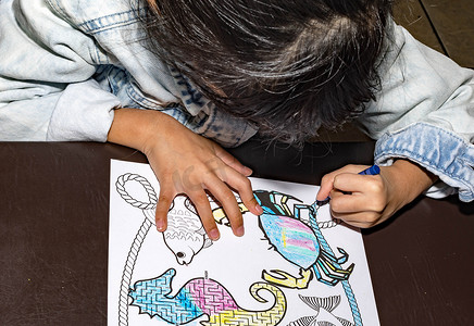 漂亮的亚洲孩子在用蜡笔和涂色本做涂色活动时是左撇子