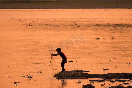 亚洲女人在河里钓鱼，夕阳下的剪影