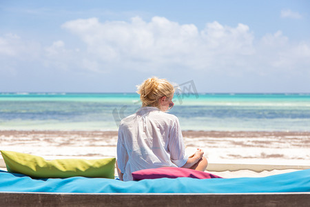 在豪华躺椅上放松的女人，举起双臂，在美丽的海滩上享受暑假。