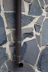 排水管摄影照片_在不同颜色的石块背景下的排水管。