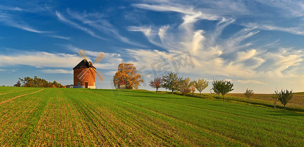 美丽的秋天风景与老风车在日落和美丽的蓝天白云。