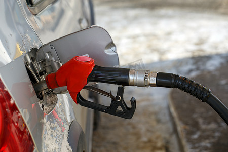 红色加油摄影照片_银色金属汽车在冬日加油站加油 — 有选择性聚焦和模糊背景的特写