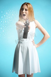 一件白色礼服的美丽的女孩拿着有发胶的瓶