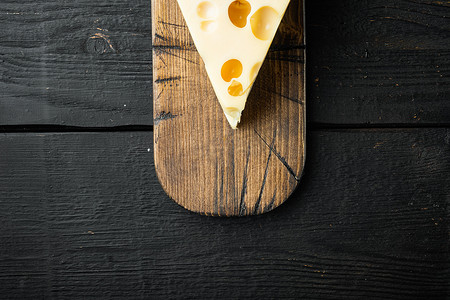 早餐铺摄影照片_Maasdam 奶酪，黑色木质背景，顶视图平铺，带有文本复制空间
