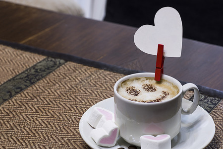 桌上放着加牛奶的咖啡，还有一张心形卡片，上面有祝贺的地方。