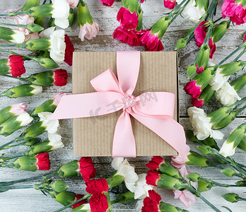 白色风化窝上礼品盒周围的彩色康乃馨花