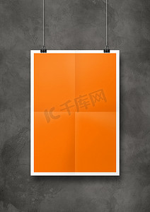 夹子挂摄影照片_挂在带夹子的混凝土墙上的橙色折叠海报