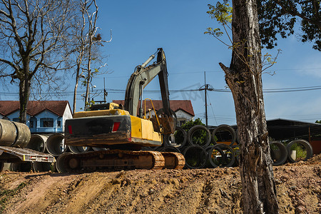 大型推土机摄影照片_使用挖掘机将大型管道转移到车辆上。