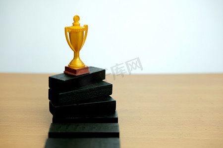 领奖摄影照片_站在白色领奖台上的金色奖杯