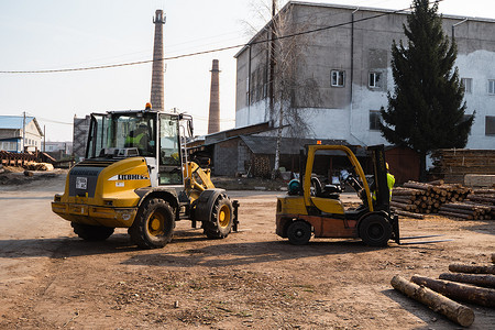 LUTSK, UKRAINE - May 10, 2020：黄色轮式装载机挖掘机在锯木厂工作。