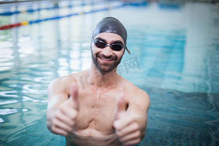 微笑的男人戴着泳帽和护目镜竖起大拇指
