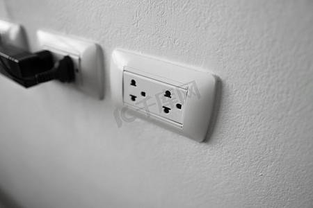 通用电气摄影照片_白墙上的白色通用电源插座插头。