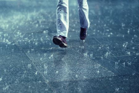 奔跑背摄影照片_人行道上的雨滴雨中奔跑的人