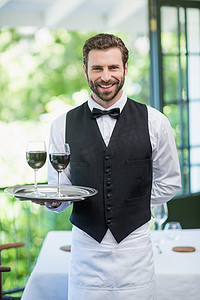 餐厅男服务员拿着带酒杯的托盘