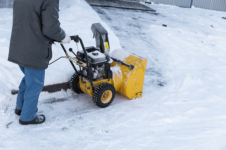 暴风雪过后，男子用造雪机清理车道。