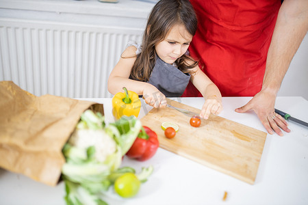 小女孩和她父亲在砧板上切蔬菜